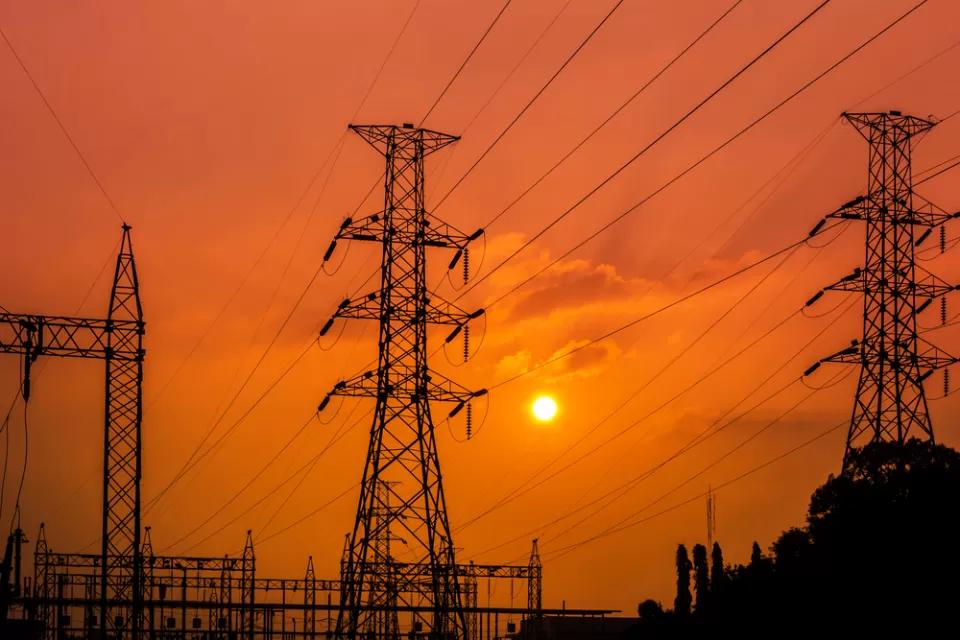 Power lines and towers at a substation against a red sunset backdrop